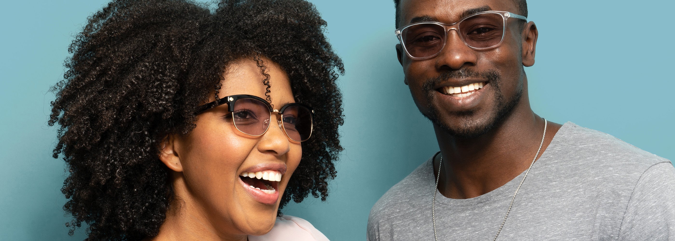 a man and woman smiling wearing axon optics powered by avulux migraine lenses on a blue background